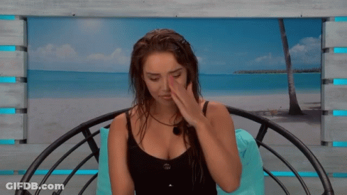 A Woman In A Black Tank Top Sits In A Chair With A Picture Of A Beach In The Background GIF