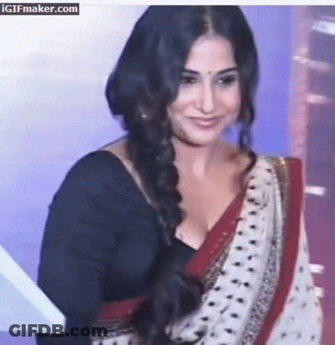 A Woman In A Black Top And A White And Red Polka Dot Saree Is Smiling GIF