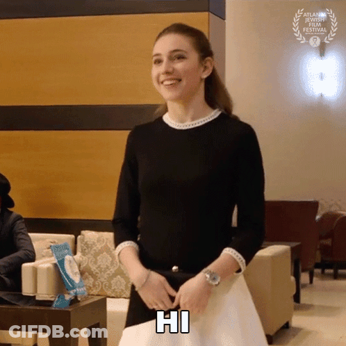 A Woman In A Black Top Is Smiling And Holding A Piece Of Paper That Says Hi GIF