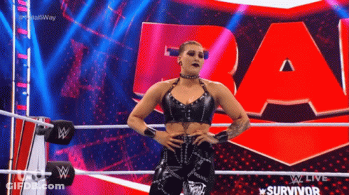 A Woman In A Black Top Is Standing In A Wrestling Ring . GIF