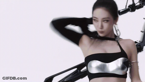A Woman In A Black Top Is Standing Next To A Robot Arm . GIF