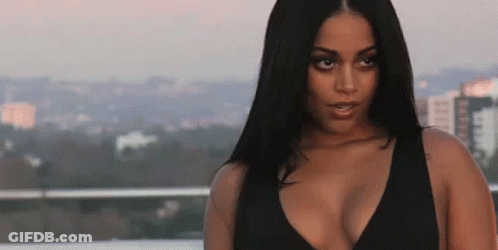 A Woman In A Black Top Is Standing On A Balcony Overlooking The City . GIF