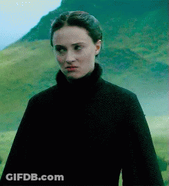 A Woman In A Black Turtleneck Is Standing In A Field GIF