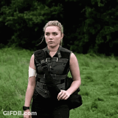 A Woman In A Black Vest Is Standing In A Field . GIF