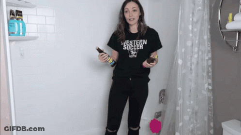A Woman In A Black Western Soccer Shirt Holds A Bottle GIF
