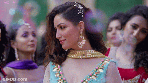 A Woman In A Blue And Gold Dress Stands In Front Of A Crowd Of Women GIF
