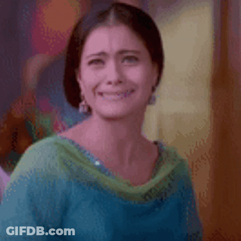 A Woman In A Blue And Green Dress Is Smiling And Making A Funny Face . GIF
