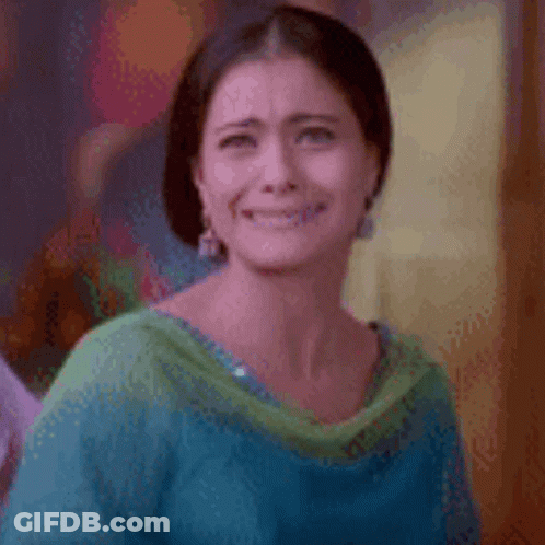 A Woman In A Blue And Green Shirt Is Smiling And Making A Funny Face . GIF
