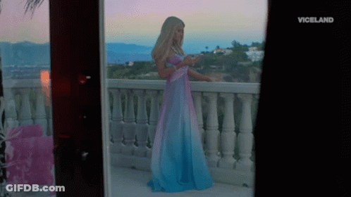 A Woman In A Blue And Pink Dress Is Standing On A Balcony With The Word Viceland On The Bottom Right GIF