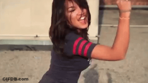 A Woman In A Blue And Red Striped Shirt Is Dancing And Making A Funny Face . GIF