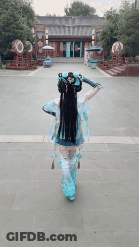 A Woman In A Blue And White Costume Is Walking In Front Of A Building GIF