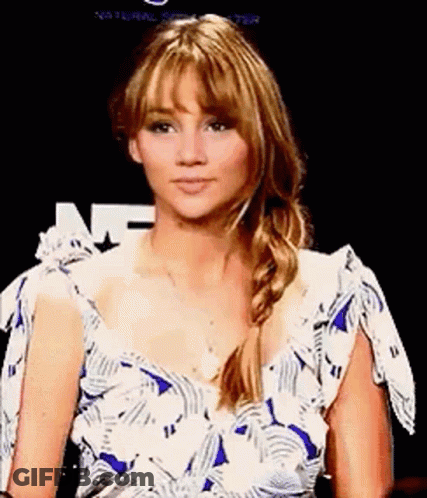 A Woman In A Blue And White Dress Is Sitting In Front Of A Black Background . GIF
