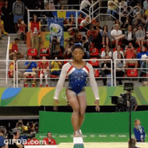 A Woman In A Blue And White Leotard Is Balancing On A Balance Beam In Front Of A Crowd GIF