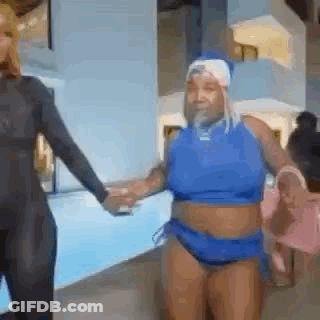 A Woman In A Blue Bathing Suit Is Holding Hands With Another Woman . GIF