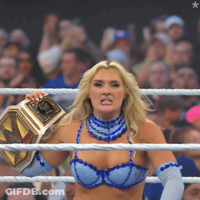 A Woman In A Blue Bra And Blue Gloves Is Holding A Wrestling Belt GIF