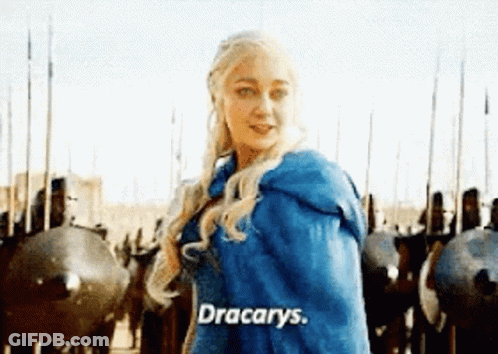 A Woman In A Blue Cape Is Standing In Front Of A Row Of Soldiers And Shields . GIF