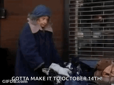 A Woman In A Blue Coat Is Pushing A Shopping Cart With A Bag Of Clothes . GIF