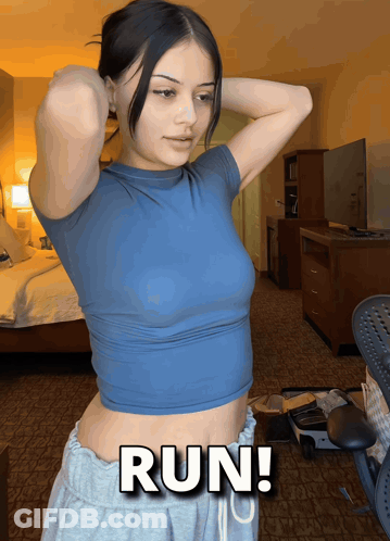 A Woman In A Blue Crop Top Stands In A Room With The Words Run Written On The Bottom GIF