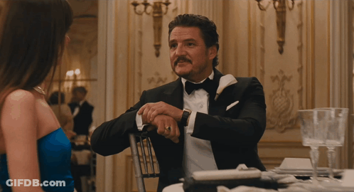 A Woman In A Blue Dress And A Man In A Suit Are Looking At Each Other GIF