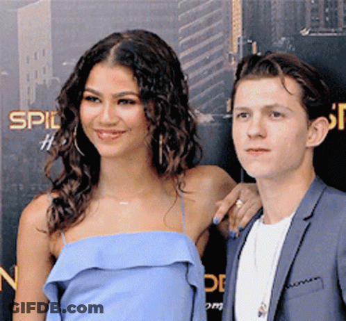 A Woman In A Blue Dress And A Man In A Suit Are Posing For A Picture GIF