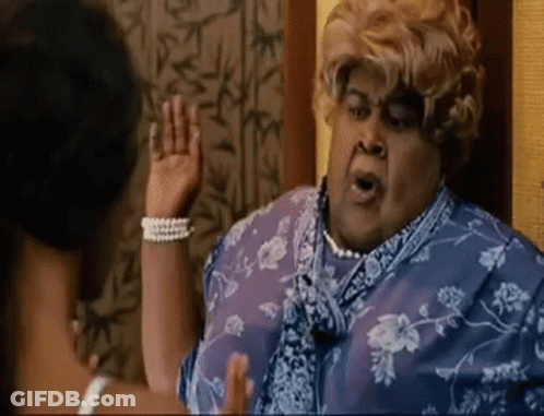 A Woman In A Blue Dress And Pearls Is Talking To Another Woman . GIF