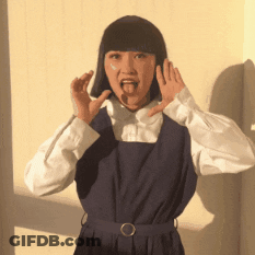 A Woman In A Blue Dress And White Shirt Is Making A Funny Face GIF