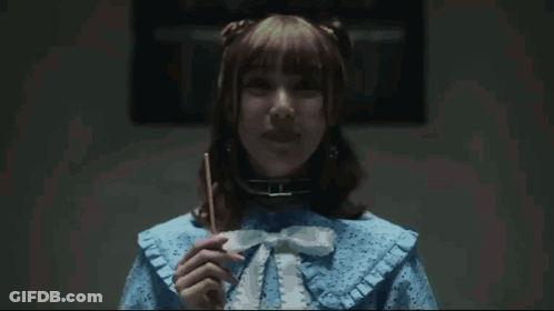 A Woman In A Blue Dress Has Her Finger On Her Lips GIF