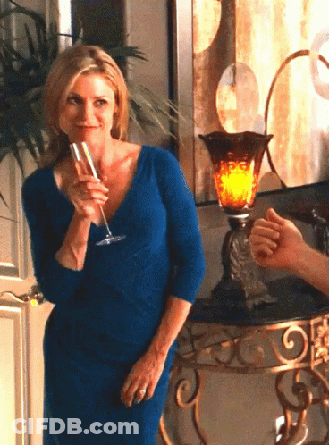 A Woman In A Blue Dress Holds A Glass Of Champagne GIF