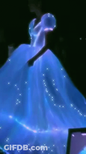 A Woman In A Blue Dress Is Dancing In Front Of A Computer Screen GIF