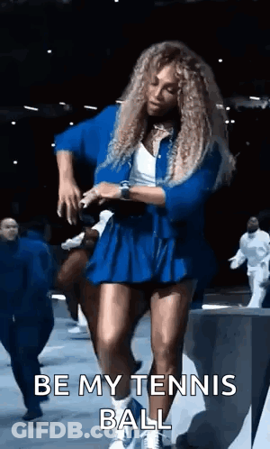 A Woman In A Blue Dress Is Dancing On A Stage And Says `` Be My Tennis Ball '' . GIF