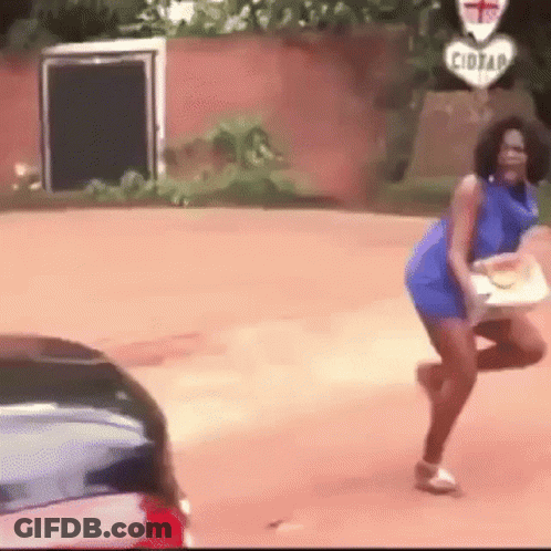 A Woman In A Blue Dress Is Dancing On The Side Of The Road . GIF