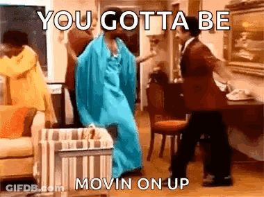 A Woman In A Blue Dress Is Dancing With A Man In A Suit In A Living Room . GIF