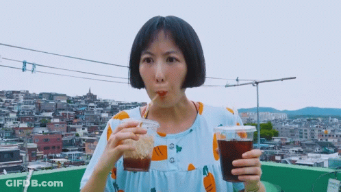 A Woman In A Blue Dress Is Drinking From A Plastic Cup GIF