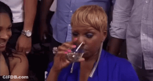 A Woman In A Blue Dress Is Drinking Water From A Glass . GIF