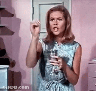 A Woman In A Blue Dress Is Holding A Glass Of Water In Her Hand . GIF