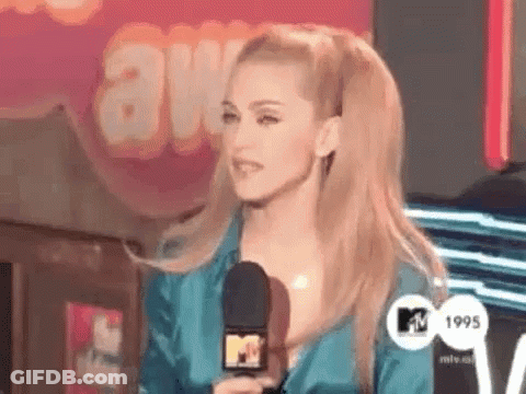 A Woman In A Blue Dress Is Holding A Microphone In Front Of A Sign That Says Awards . GIF