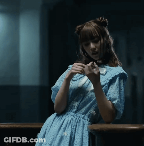 A Woman In A Blue Dress Is Holding A White Object GIF