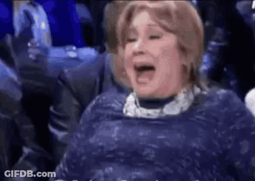 A Woman In A Blue Dress Is Laughing With Her Mouth Open . GIF