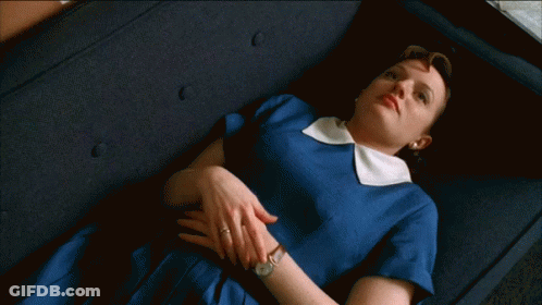 A Woman In A Blue Dress Is Laying Down On A Couch GIF