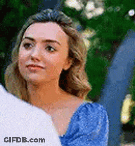 A Woman In A Blue Dress Is Looking Over Her Shoulder At A Man In A White Shirt . GIF