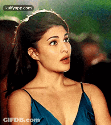 A Woman In A Blue Dress Is Making A Surprised Face . GIF