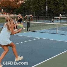 A Woman In A Blue Dress Is Playing Tennis On A Tennis Court GIF