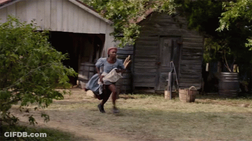 A Woman In A Blue Dress Is Running In Front Of An Old Building GIF