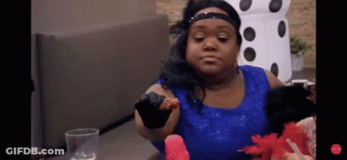 A Woman In A Blue Dress Is Sitting At A Table Eating A Piece Of Food GIF