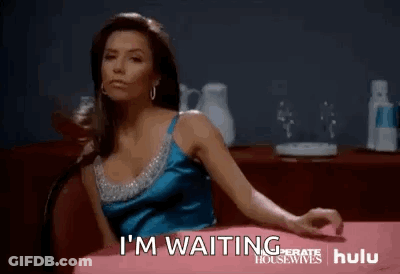 A Woman In A Blue Dress Is Sitting At A Table With Her Arms Outstretched . GIF