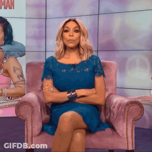 A Woman In A Blue Dress Is Sitting In A Pink Chair GIF