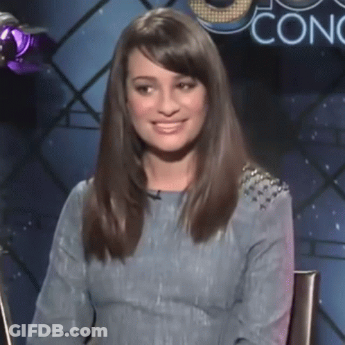 A Woman In A Blue Dress Is Smiling In Front Of A Sign That Says Conc GIF