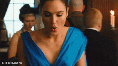 A Woman In A Blue Dress Is Standing In A Room With Her Mouth Open . GIF