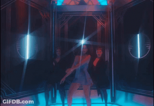 A Woman In A Blue Dress Is Standing In A Room With Two Other Women GIF