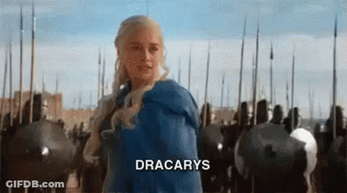 A Woman In A Blue Dress Is Standing In Front Of A Row Of Soldiers With The Word Dracarys On The Bottom . GIF